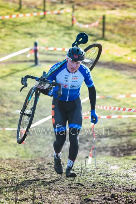 Veldrijder met fiets over schouder